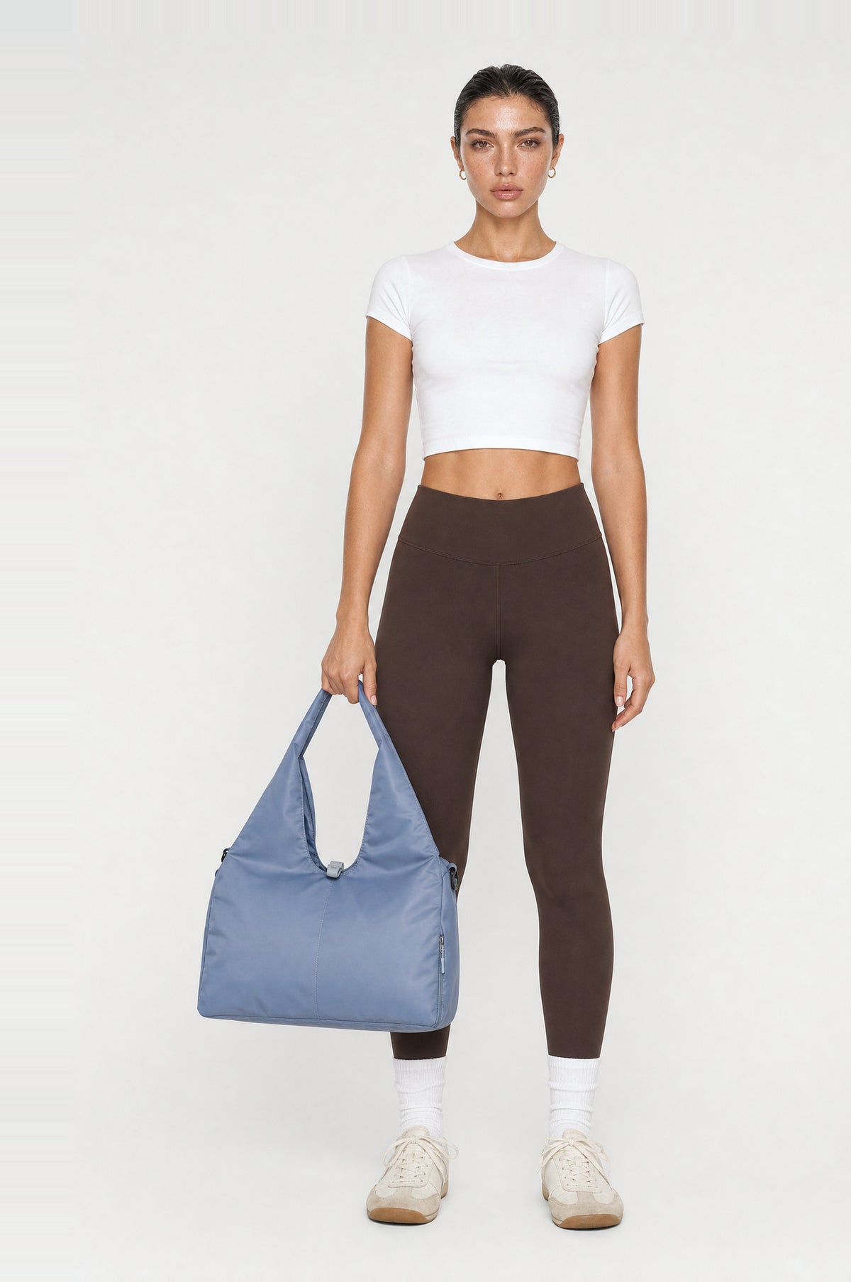 The Greenwich Travel Bag in Misty Blue, front, held by the handle
