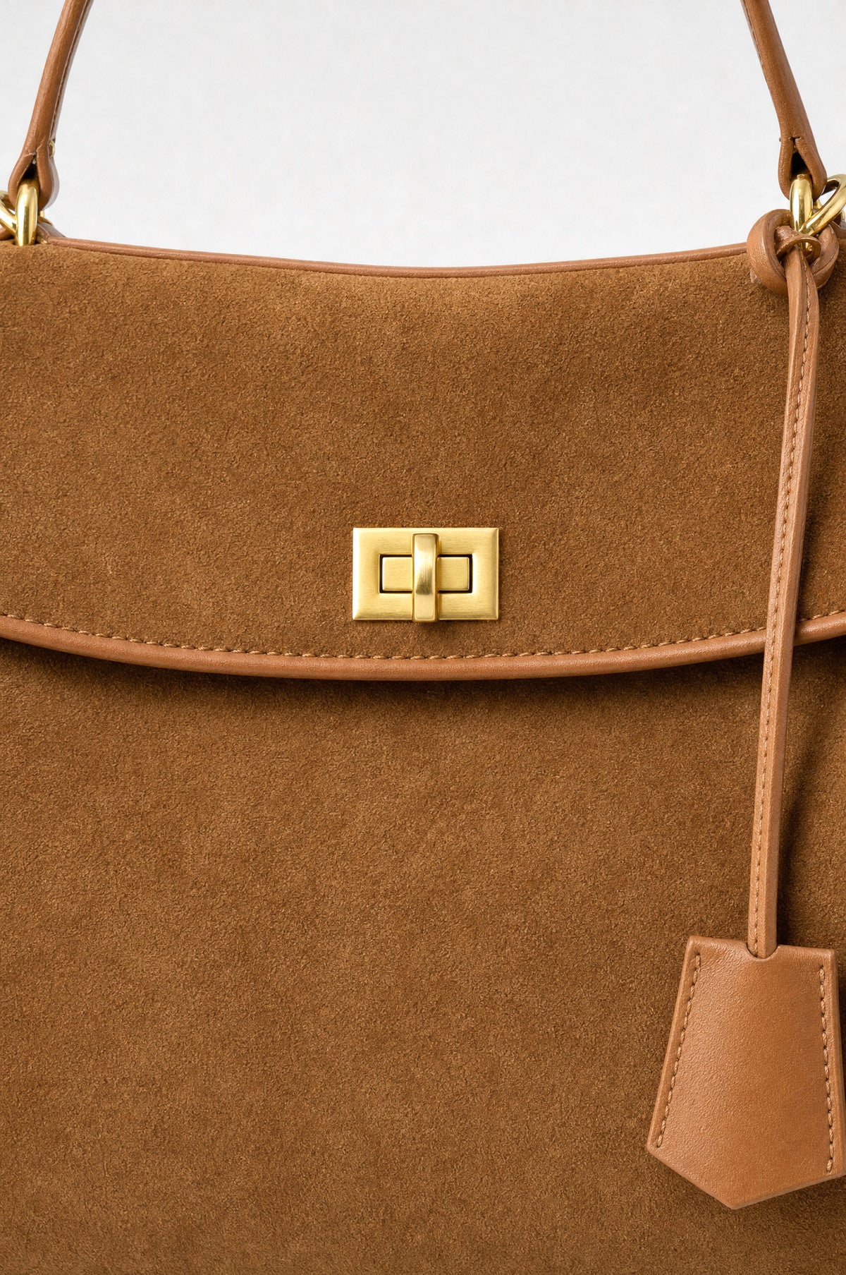 The Kensington Top-Handle Bag in Caramel, close-up of the suede, piping and turn-lock